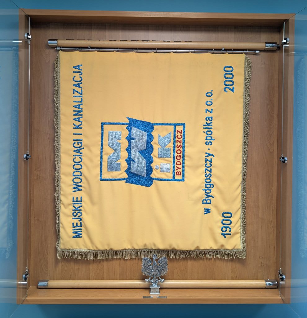 sztandar bydgoskich wodociągów umieszczony w drewnianej gablocie