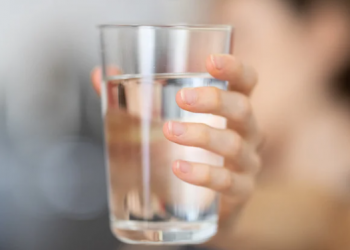 dłoń trzymająca szklankę wody