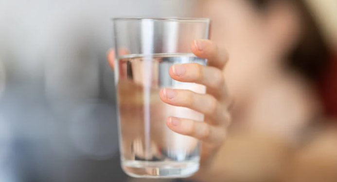 dłoń trzymająca szklankę wody