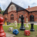 Zabytkowy budynek z elemantami gier - pionkami i kostkami - w dużym rozmiarze przed tym budynkiem