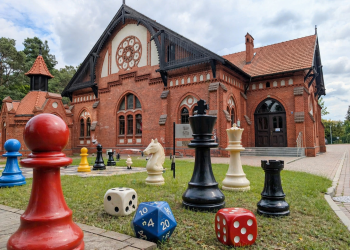 Zabytkowy budynek z elemantami gier - pionkami i kostkami - w dużym rozmiarze przed tym budynkiem
